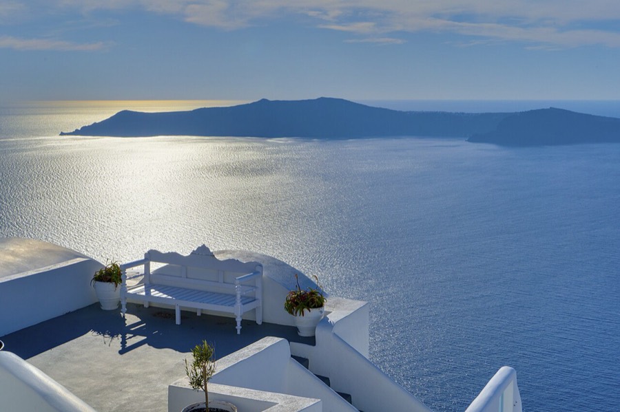A whitewashed terrace overlooking the Santorini caldera at golden hour